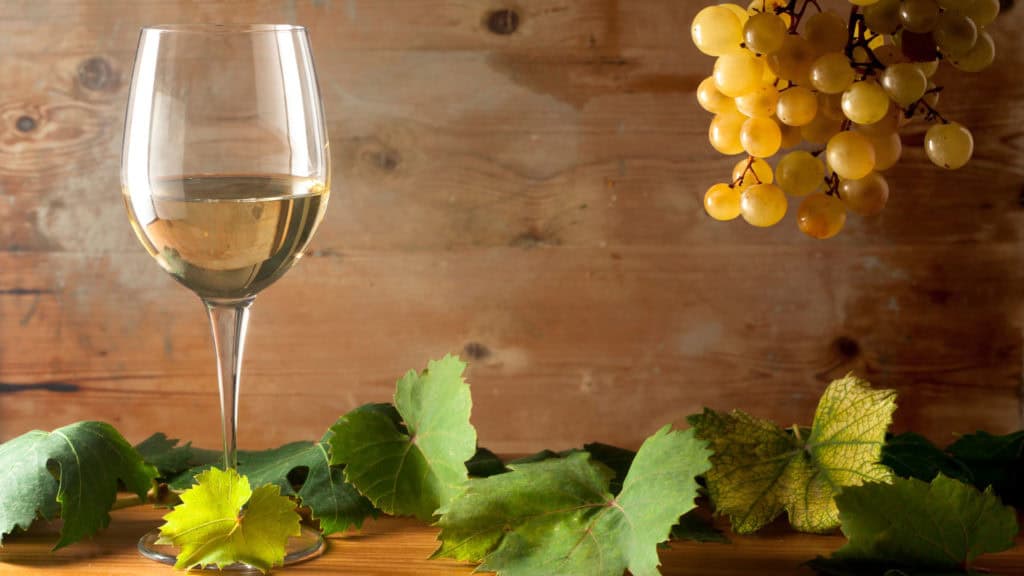 Raisins clairs d'Ermitage à côté d'un verre à vin rempli sur la table