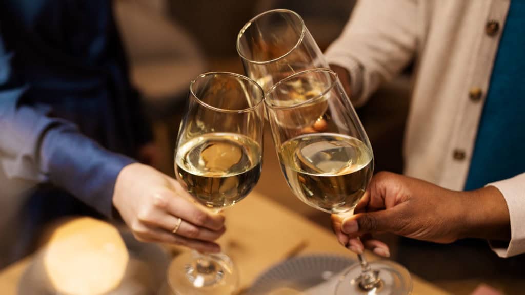 Anstossen mit Muscat bei festlicher Gelegenheit, warme Atmosphäre.