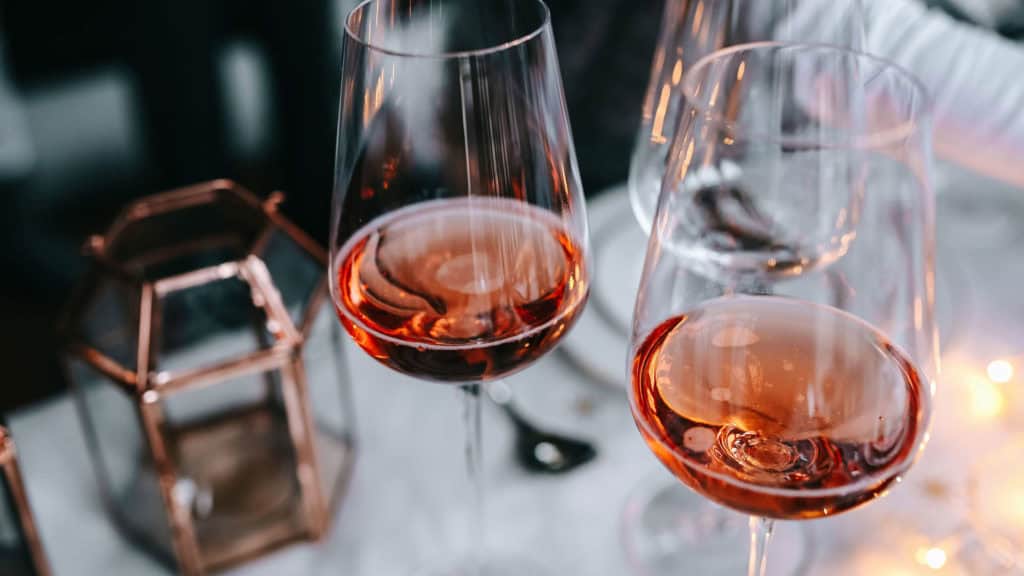 Zwei Weingläser mit Roséwein auf einem Tisch neben einer Laterne