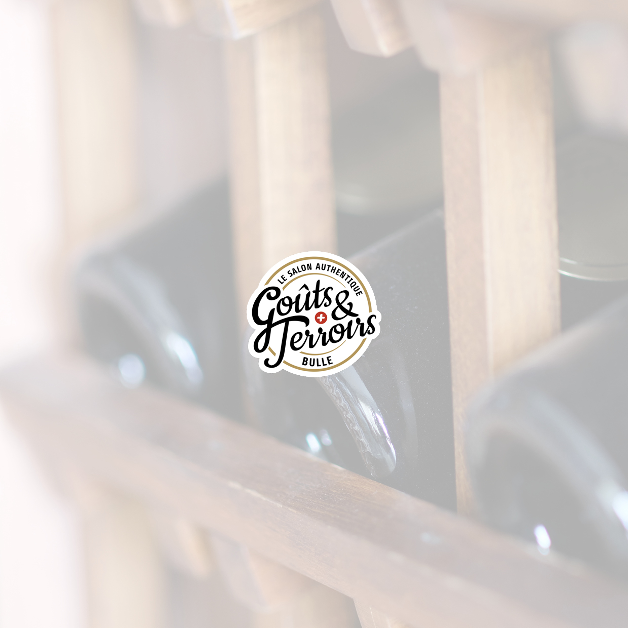 Logo mit dem Schriftzug 'Goûts & Terroirs' vor unscharfem Hintergrund von Weinflaschen in einem Holzregal