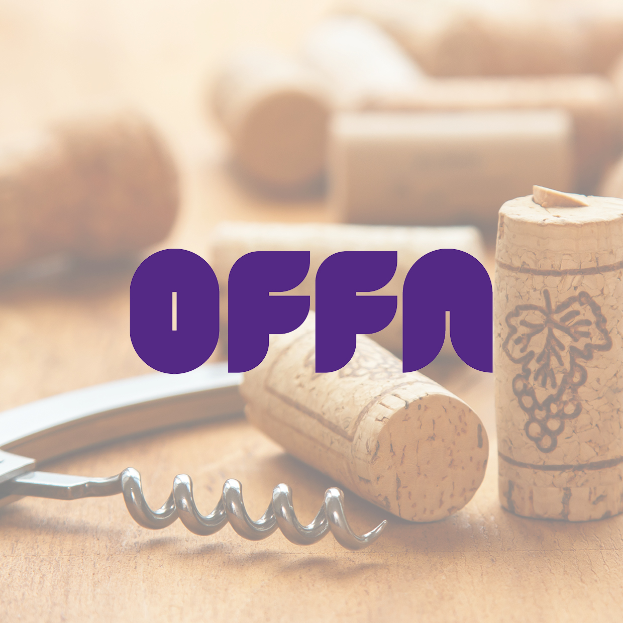 Mehrere Weinkorken und ein Korkenzieher liegen auf einem Holztisch, darüber in lila Schrift das Wort 'OFFA'