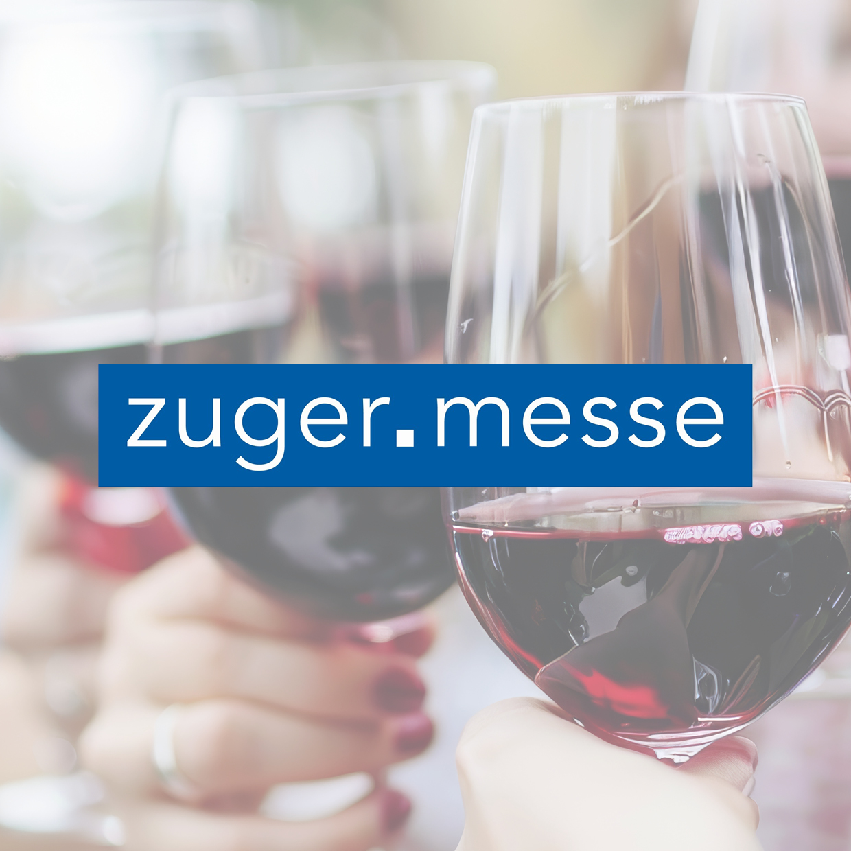 Mehrere Hände halten Weingläser mit Rotwein, darüber ein blaues Rechteck mit weisser Schrift 'zuger.messe'