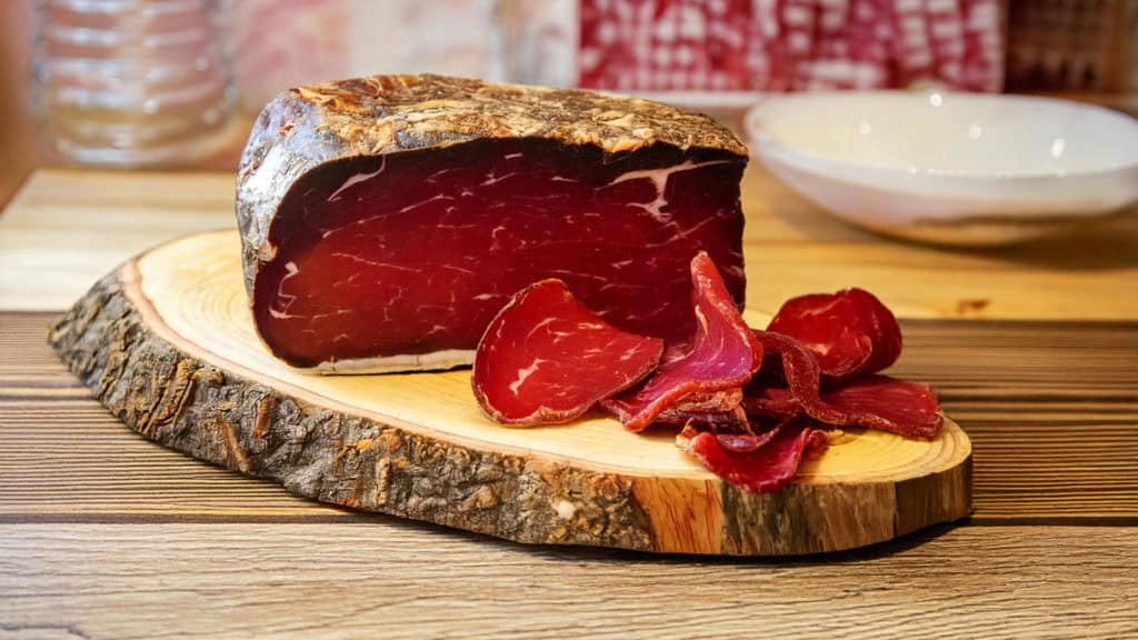 Ganzes Walliser Trockenfleisch am Stück auf Holzteller – traditionelle Fleischspezialität