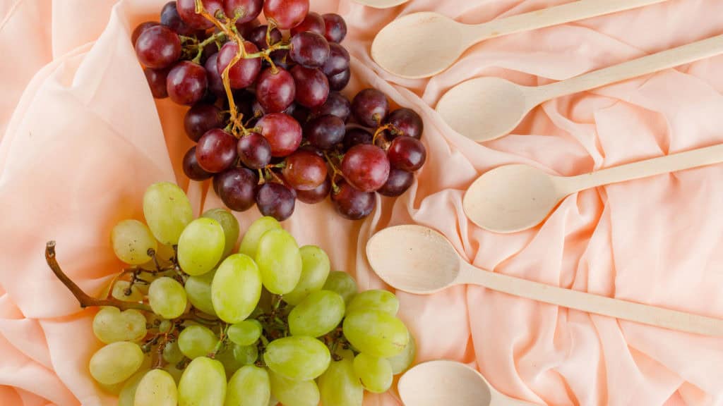 Weisse und rote Weintrauben nebeneinander auf einem Tisch, Symbol für Nährstoffe in Trauben