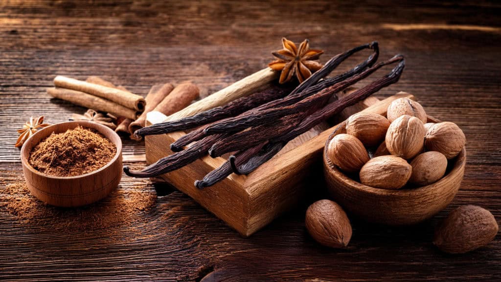 Verschiedene Weinaromen –Zimtstangen, Vanilleschoten, Sternanis, Muskatnüsse und gemahlene Gewürze auf Holzuntergrund
