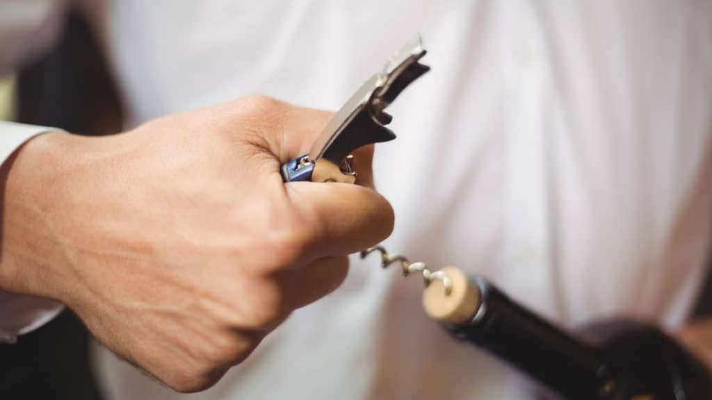 Man opens wine bottle - wine service in a restaurant or at home