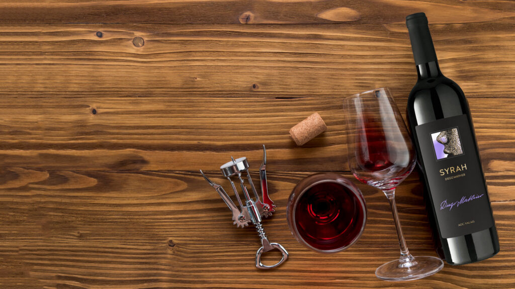 Flasche Rotwein Syrah Diego Mathier, Weinglas mit Rotwein, Korken und Korkenzieher auf Holztisch