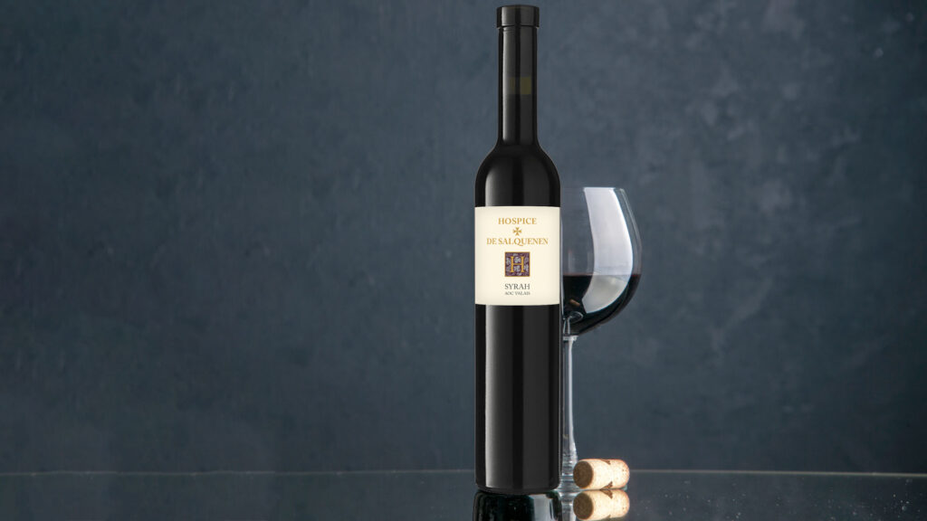 Syrah Wein im Weinglas im Hospices de Salquenen und ein Korken auf dunklem Untergrund