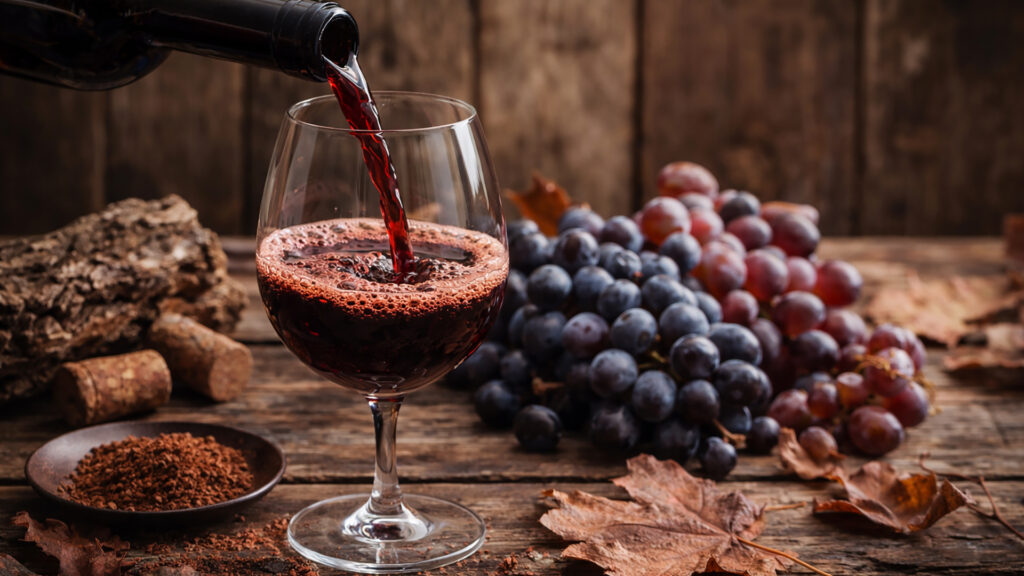 Vin rouge dans le verre avec mousse visible sur les bords, focus sur les tanins