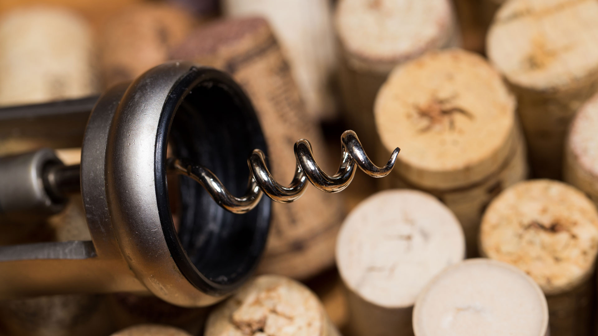 A corkscrew in front of wine corks