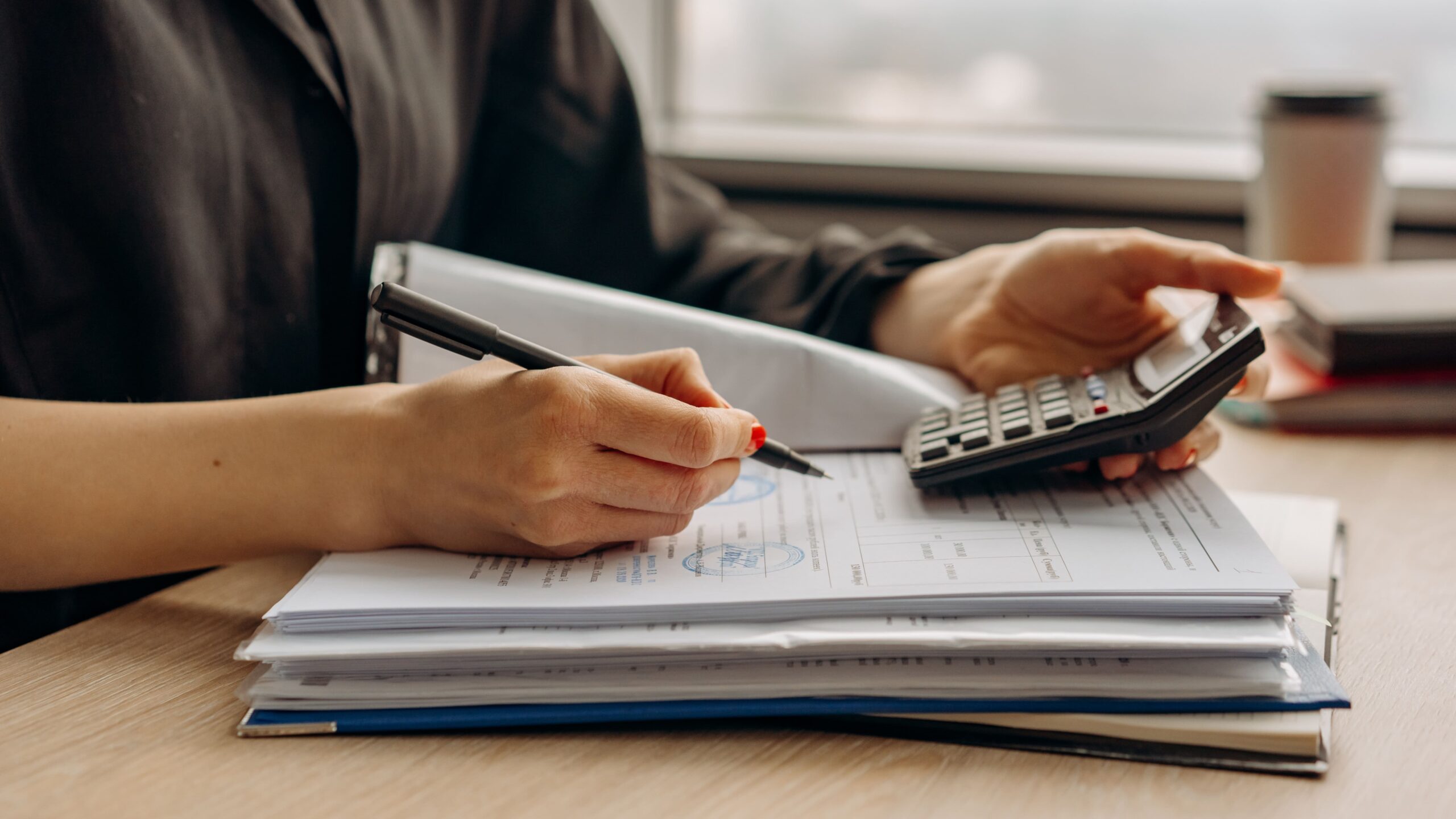 Une personne tenant une calculatrice et un stylo à la main